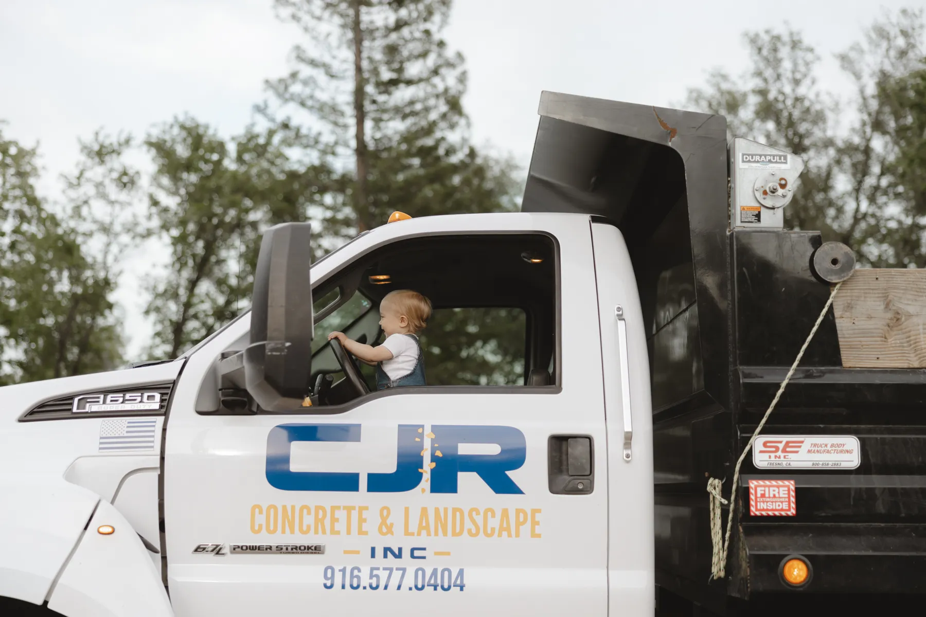 A young member of the Ray family in the driver's seat of a CJR dump truck