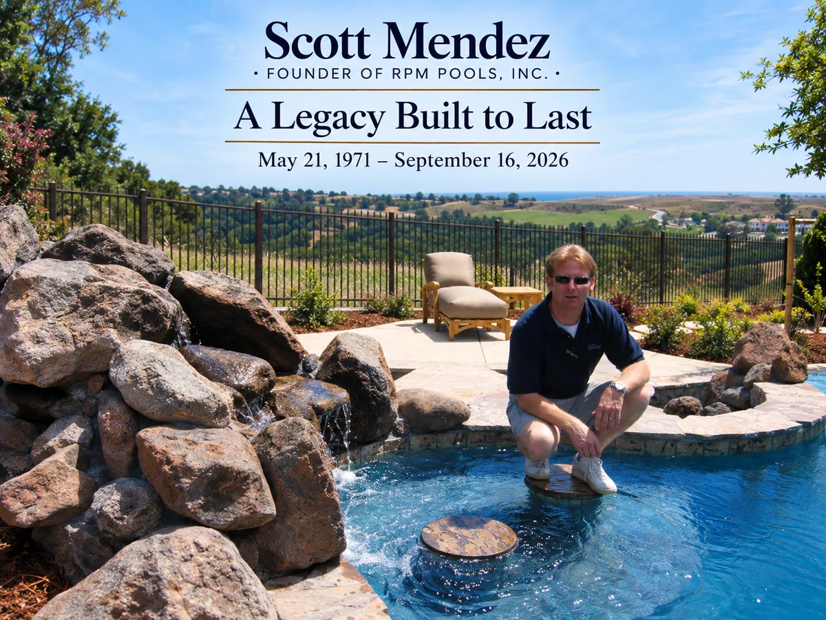 Scott Mendez, founder of RPM Pools, crouched at the edge of a backyard pool with a rock waterfall
