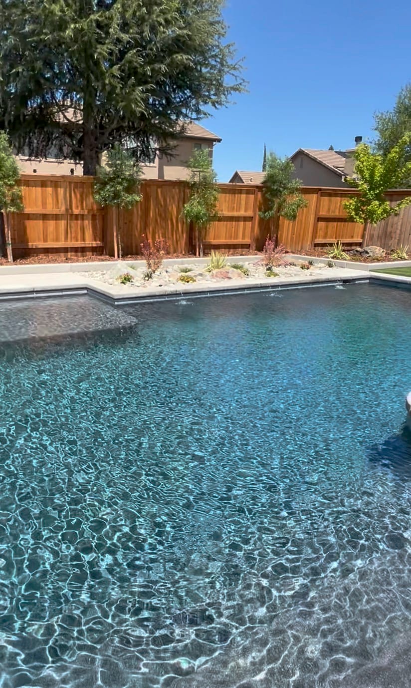A clean, finished custom pool by CJR with deck jets and landscaping