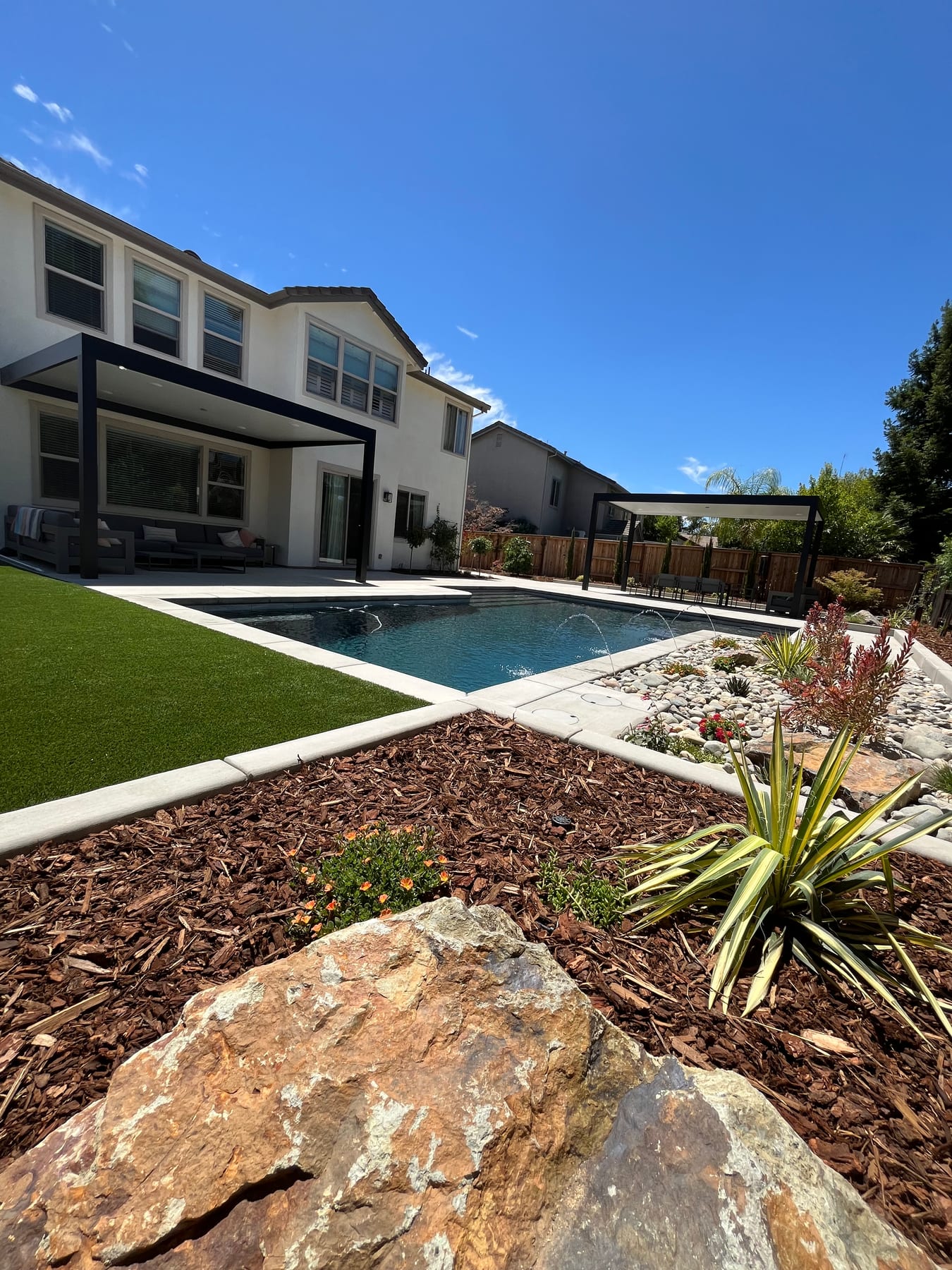 A finished CJR backyard with custom pool, pergola, turf, and landscaping in the greater Sacramento area