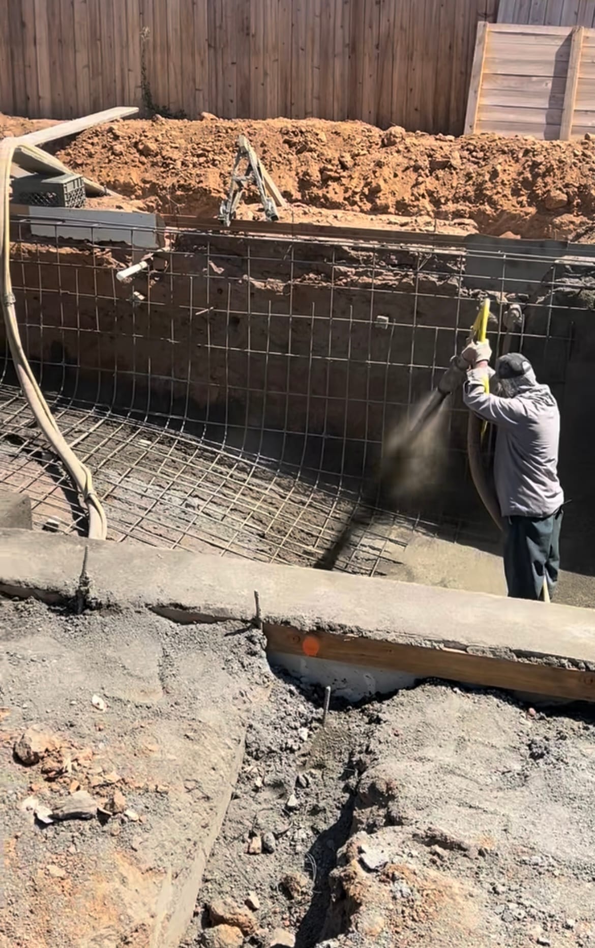 Crew applying gunite at high pressure to form the pool shell