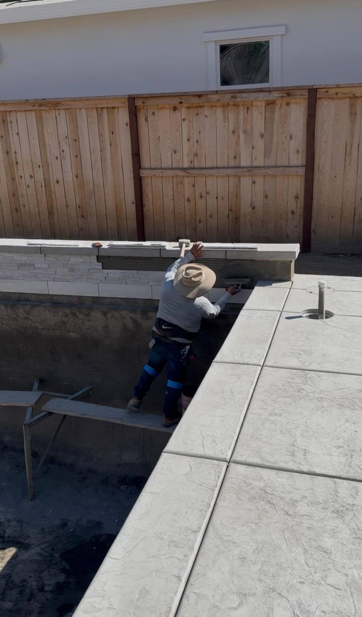 CJR installer setting tile and stone at the pool edge